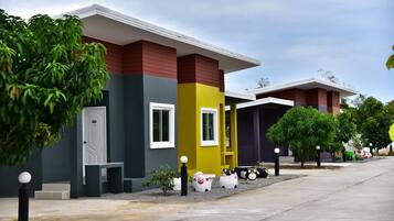 A modern building with a red, yellow, and grey facade, a white door, and a bench outside.