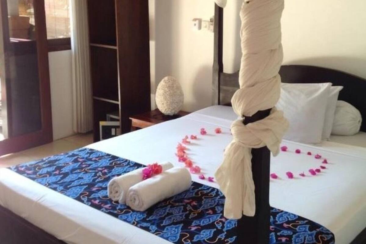 Una habitación de hotel con una cama, dosel y un arreglo floral decorativo sobre la cama.