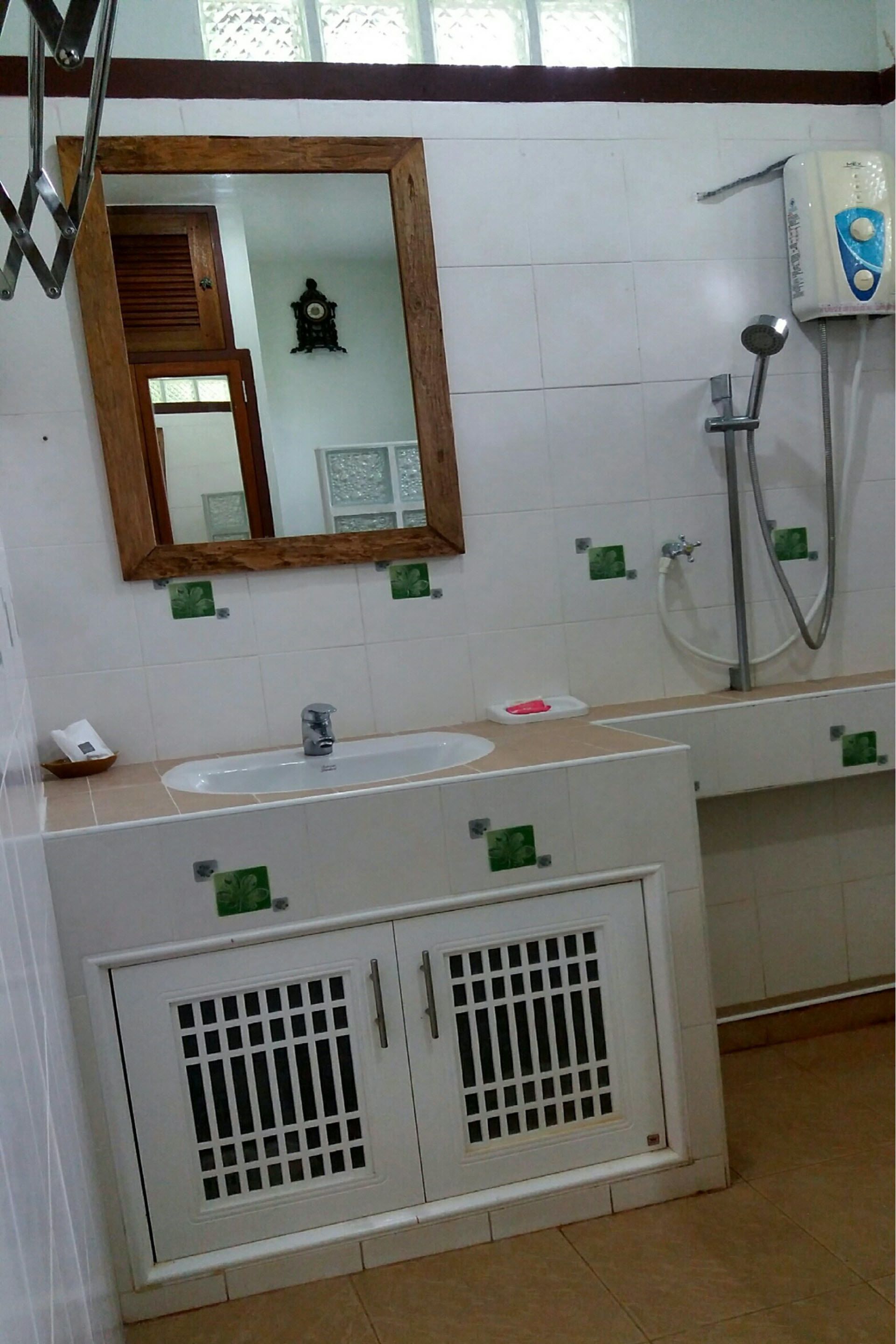Un bagno con lavandino, specchio, doccia e mobili.