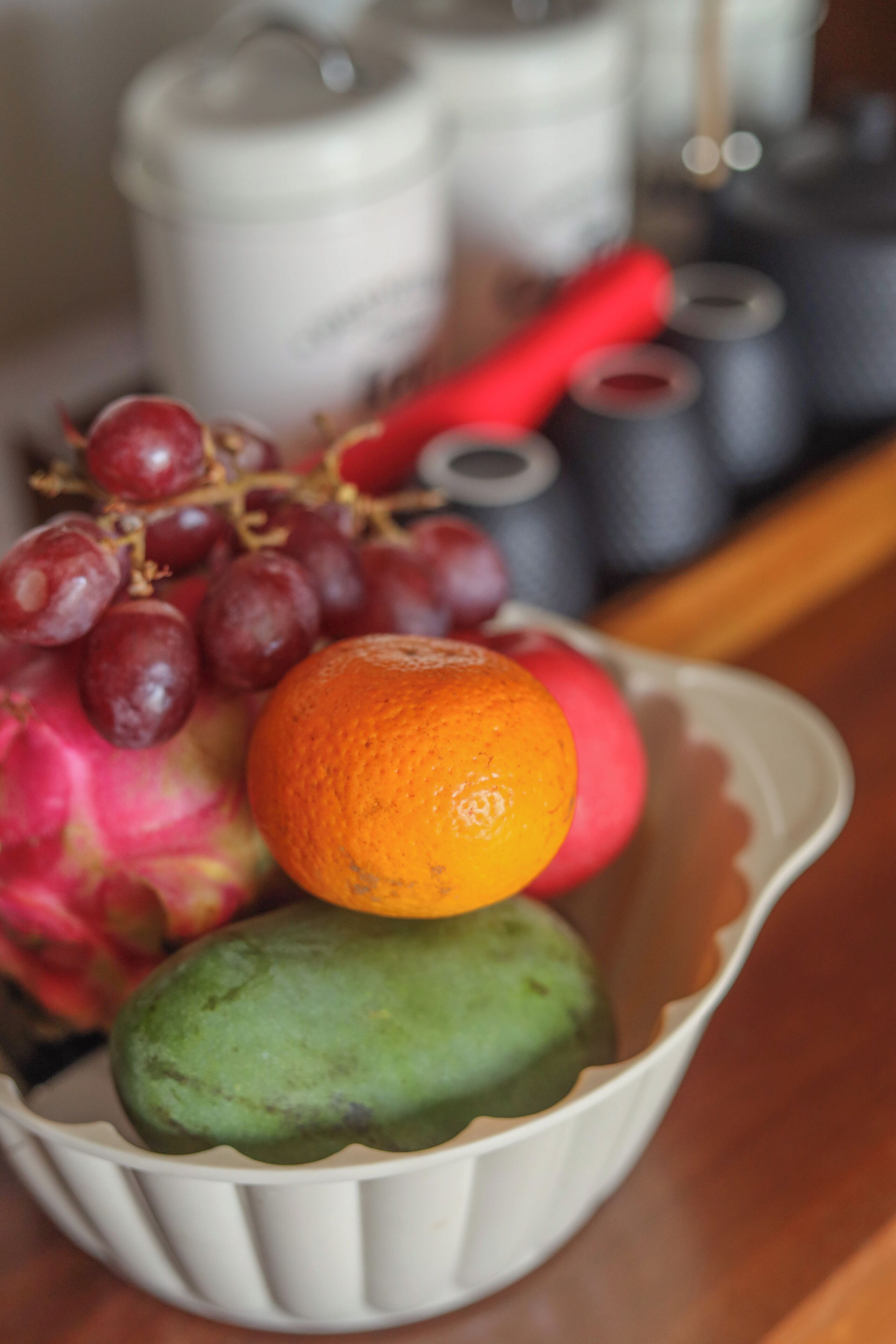 A bowl containing a variety of fruits including grapes, an orange, and a mango.