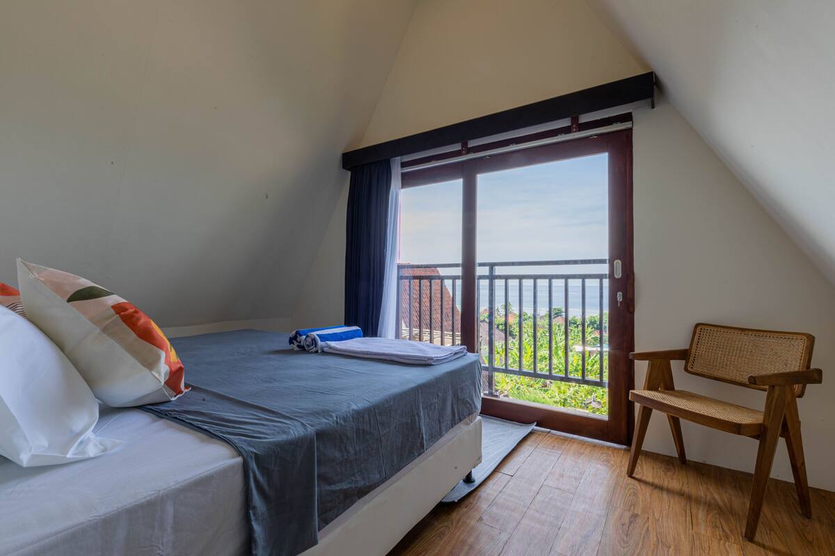 Une chambre à coucher avec un lit, une chaise et un balcon offrant une vue.