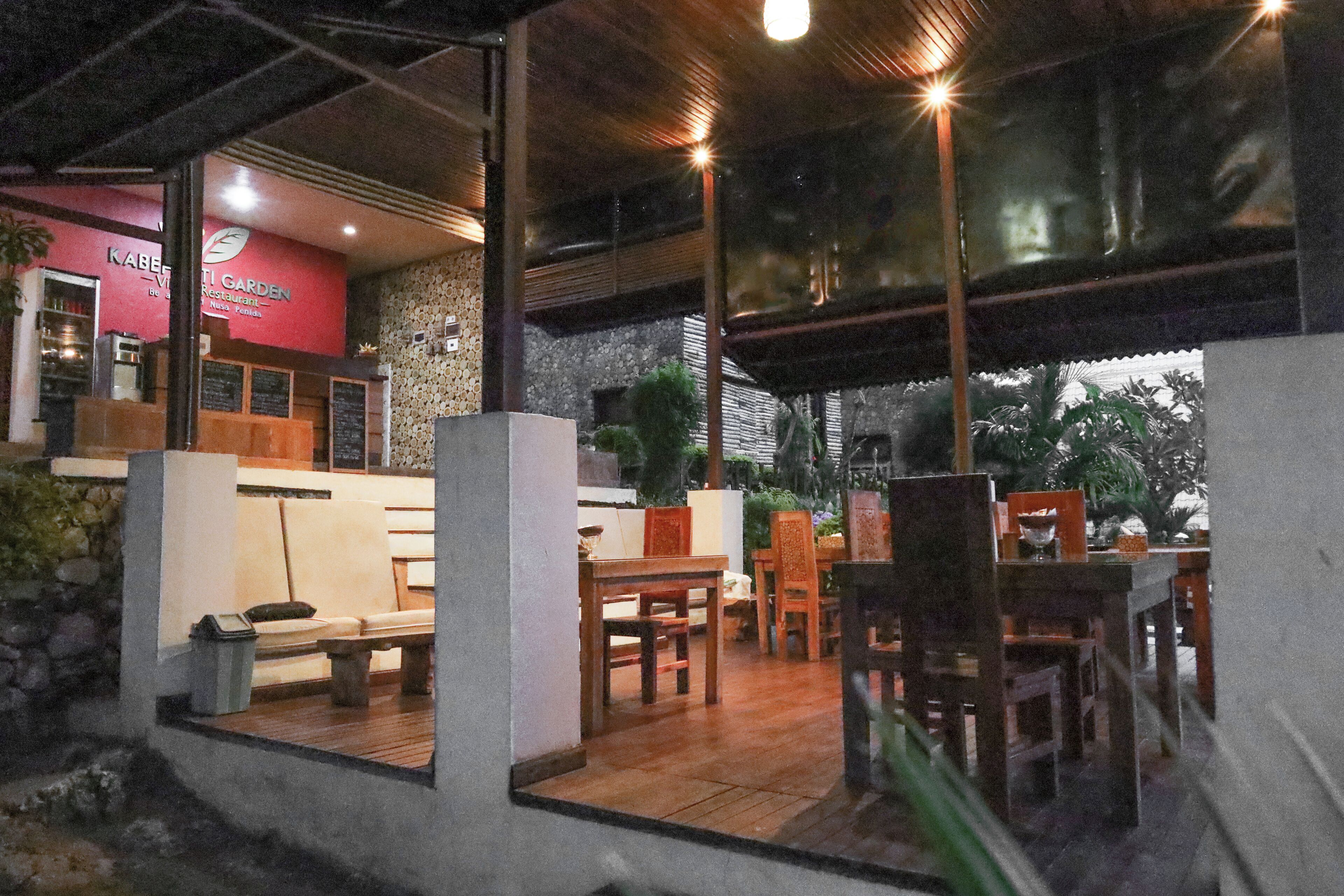 A restaurant with a stone wall, wooden furniture, and a red sign.