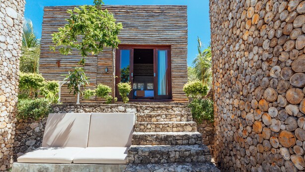 Una escalera de piedra que conduce a un edificio de madera con un ventanal grande y una puerta.