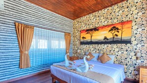 Un dormitorio con cama, cabecera de madera, un cuadro de un atardecer y una pared de troncos.