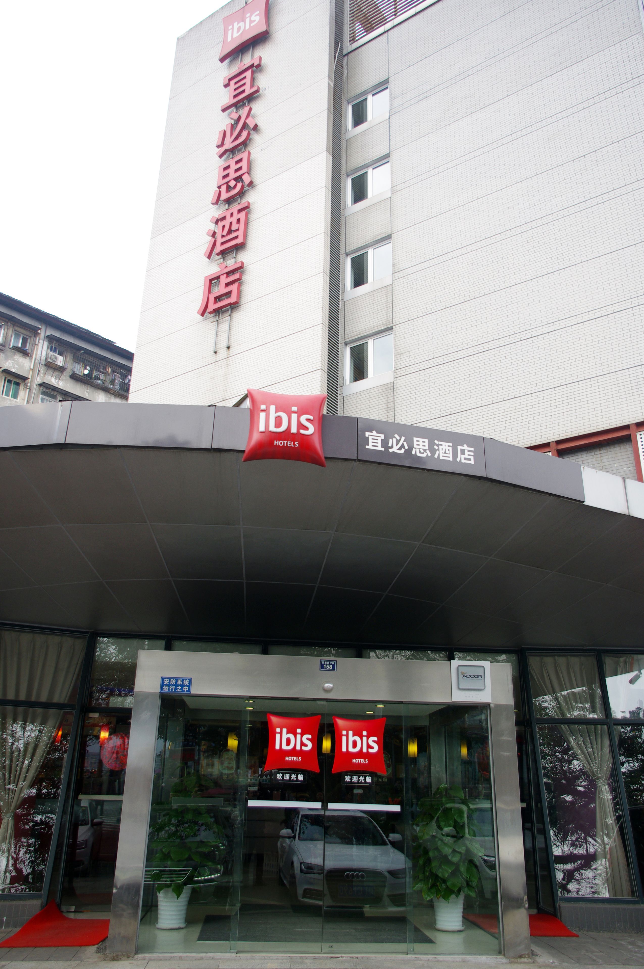 A hotel entrance with a prominent red sign and a glass facade.