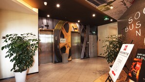 Un área de ascensor moderna con paredes metálicas y una planta grande.