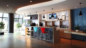 Un moderno bar con una barra curva, varias lámparas colgantes y una gran pantalla de televisión.