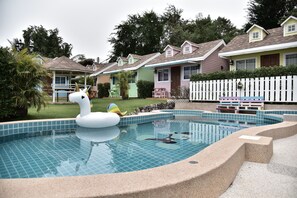 A swimming pool with a swan float, surrounded by houses with a picket fence. - Baan Tua Mor Resort (Pranburi)
