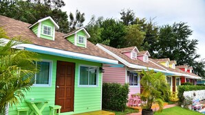Una hilera de casas coloridas, con una casa verde que tiene un porche, una mesa de madera y dos sillas.