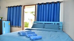 Un dormitorio con cama, cortinas azules y un refrigerador.