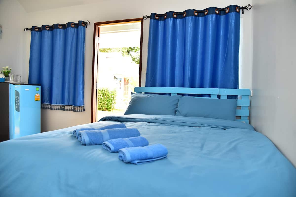 Une chambre à coucher avec un lit, des rideaux bleus et un réfrigérateur.