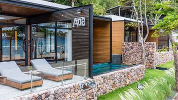 A modern cabin with a glass exterior, a stone wall, and a pool area.