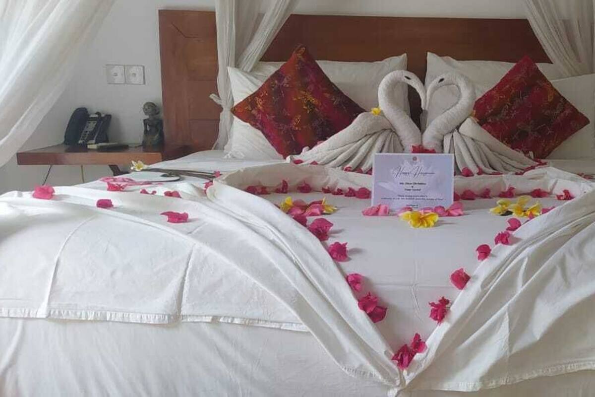 A bed with a canopy, two swan-shaped pillows, and a card on the bed.