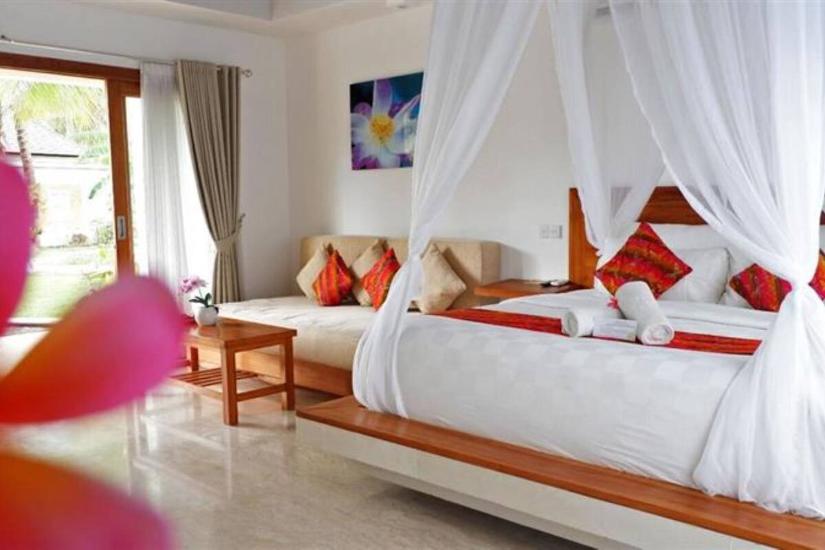 A hotel room with a bed, a bedside table, a chair, and a view of the outdoors.