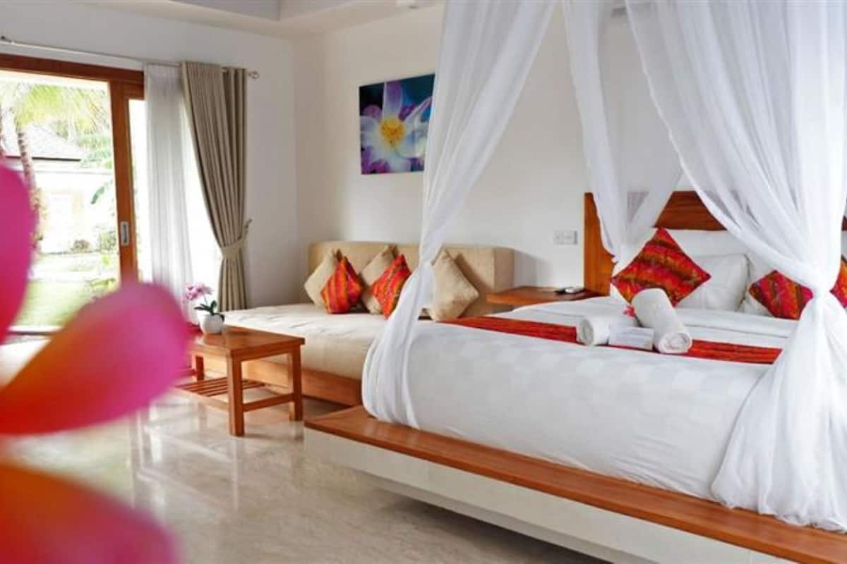 Habitación de hotel con cama, mesita de noche, una silla y vistas al exterior.