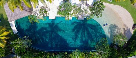 Een buitenzwembad, parasols bij het zwembad en ligstoelen