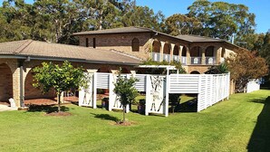 A two-story brick building with a balcony, surrounded by a well-maintained lawn and trees. - The Sanctuary at Paradise Beach (Sanctuary Point)