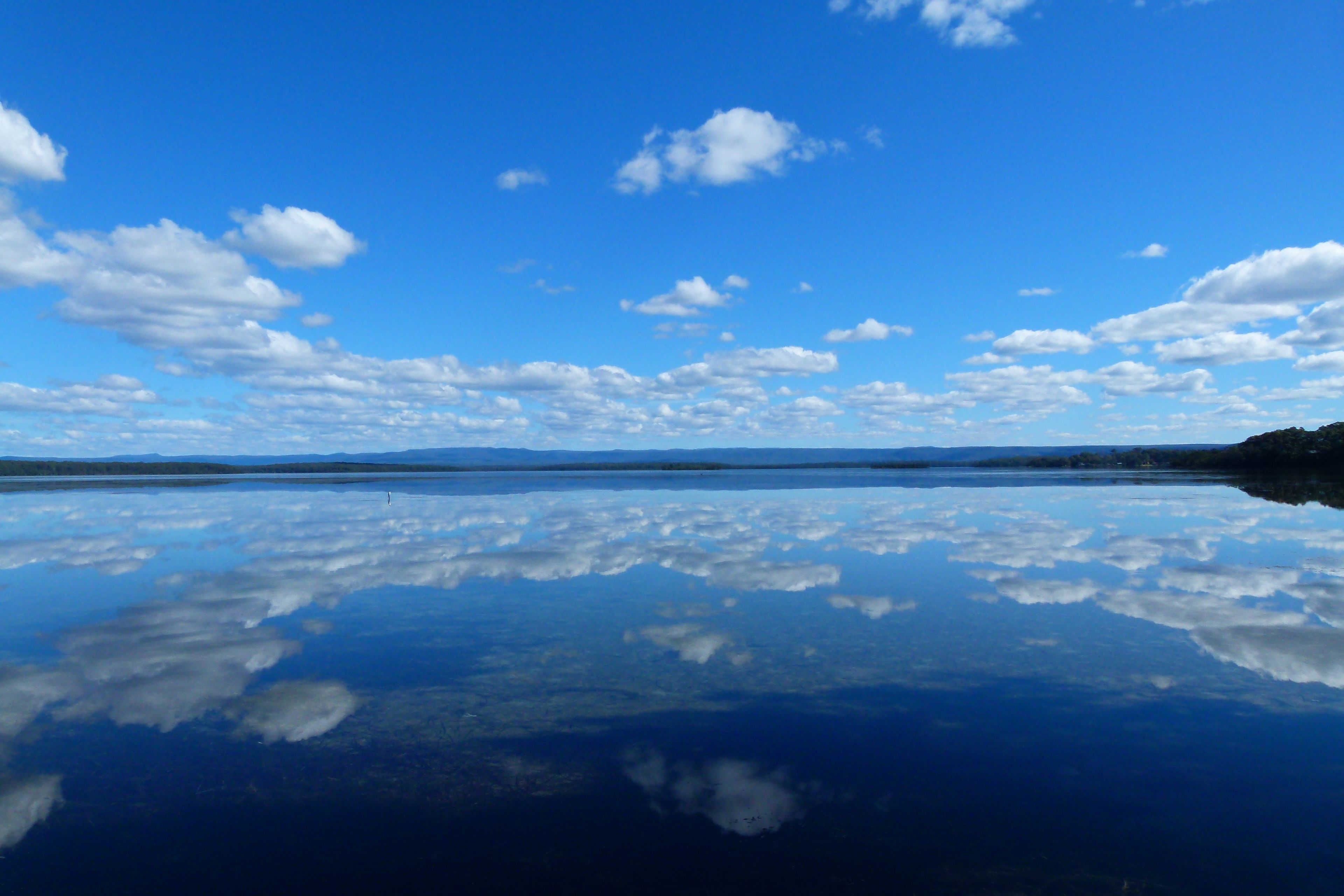 Un lac paisible dont les eaux reflètent clairement le ciel et les nuages.