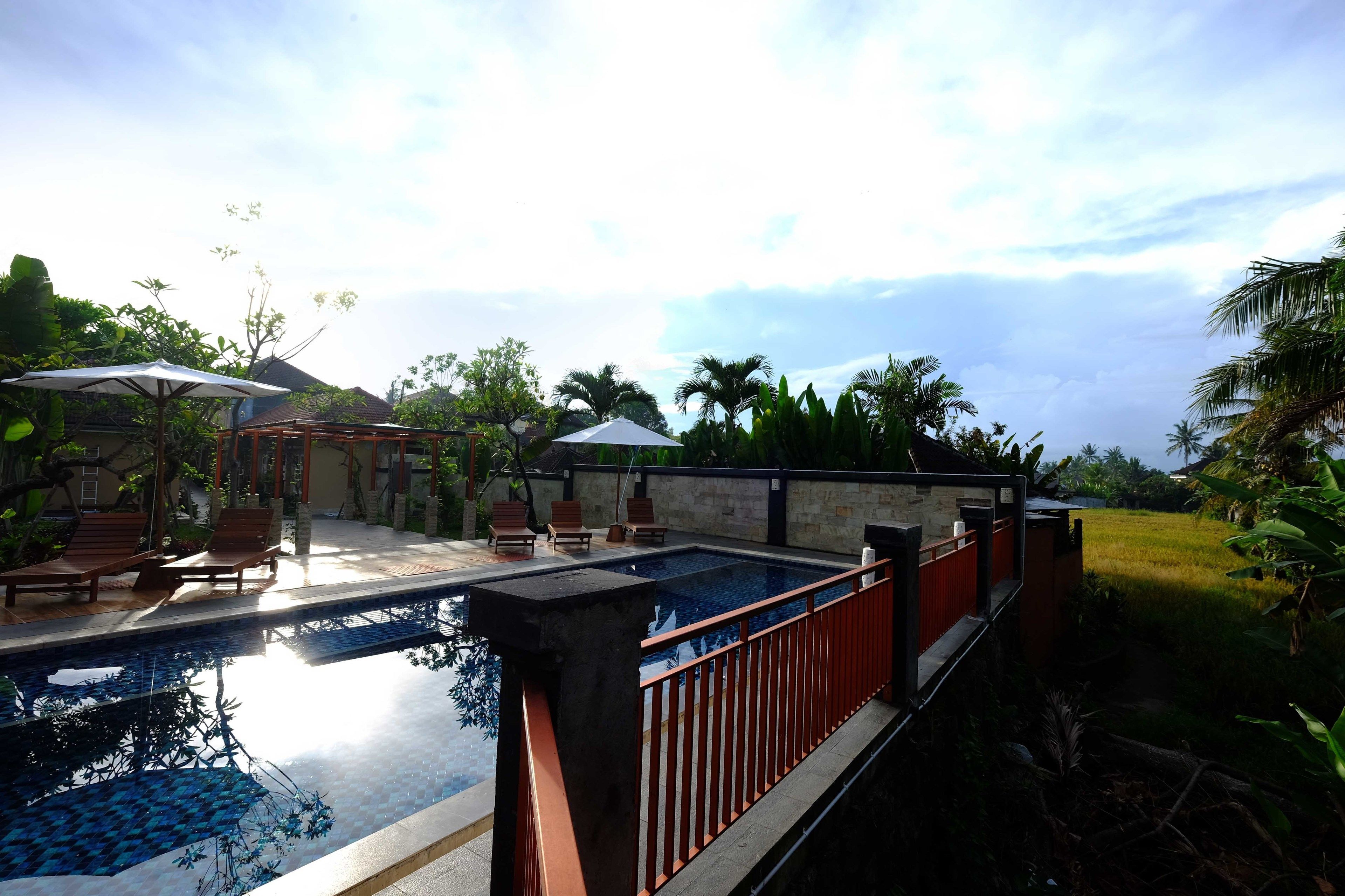 A swimming pool with a wooden deck, lounge chairs, and umbrellas.