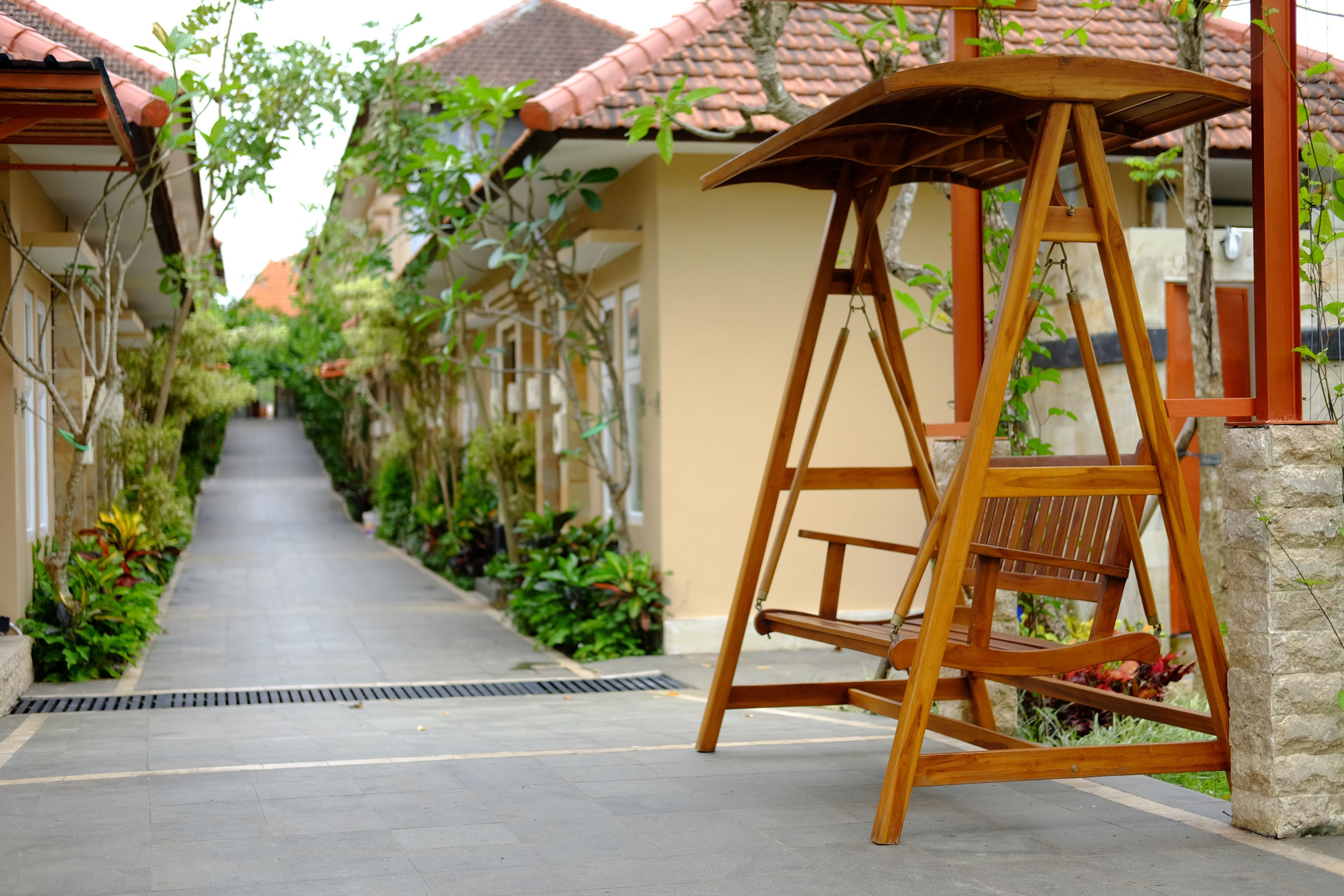 A narrow pathway flanked by buildings with red-tiled roofs and greenery.