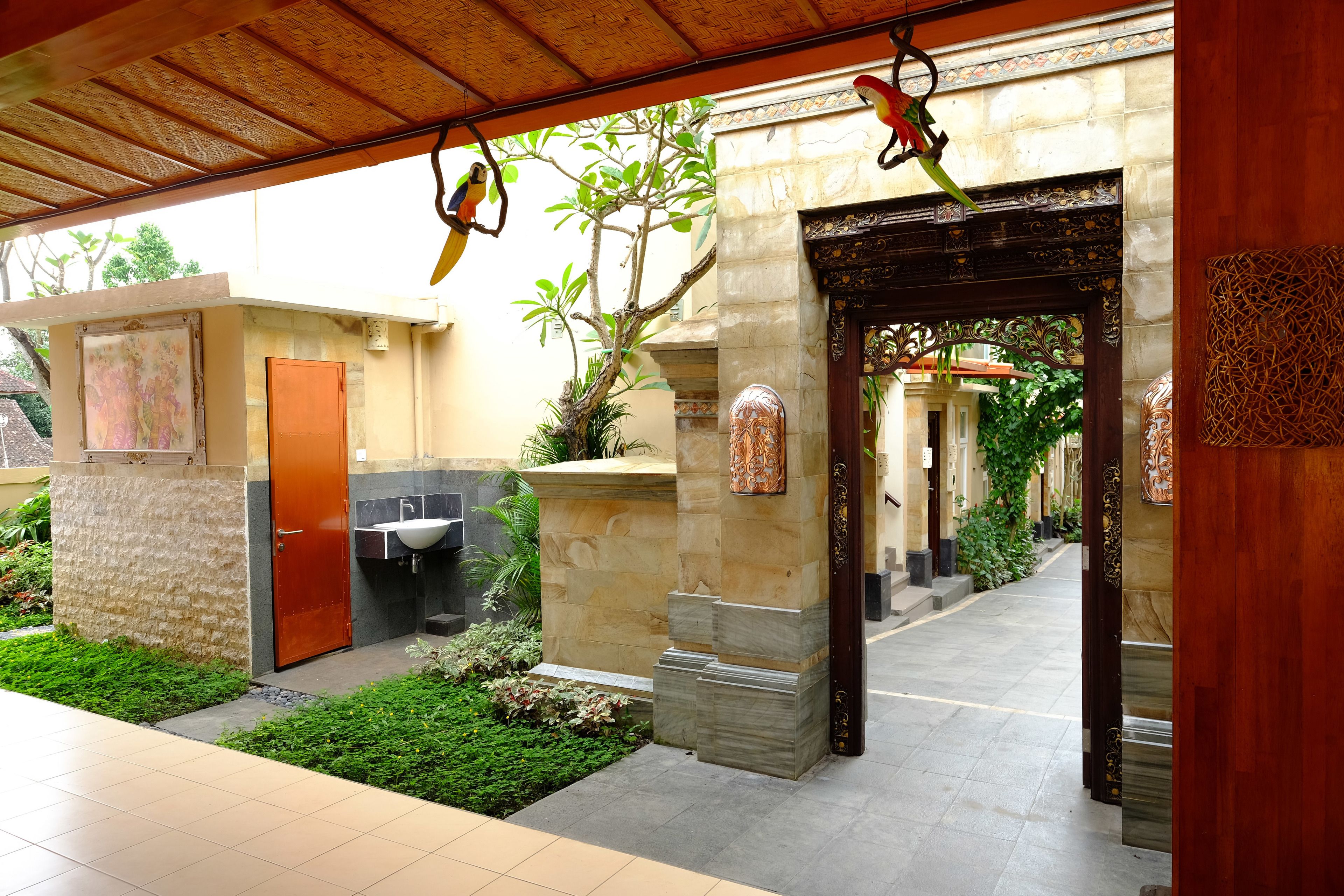 A covered outdoor area with a stone wall, a wooden door, and a tiled floor.