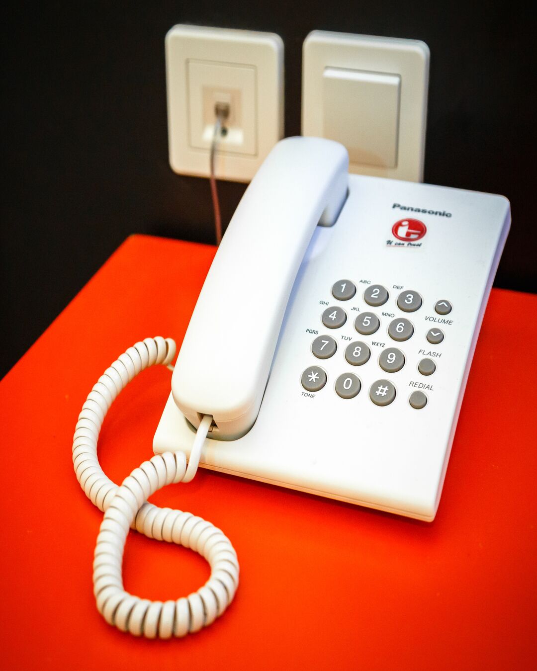 A white Panasonic telephone on an orange surface.
