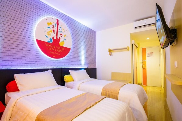 A hotel room with two beds, a wall-mounted TV, and a motivational quote.