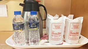 Un vassoio con bottiglie d'acqua, una macchina del caffè e sacchetti per le pulizie dell'hotel.