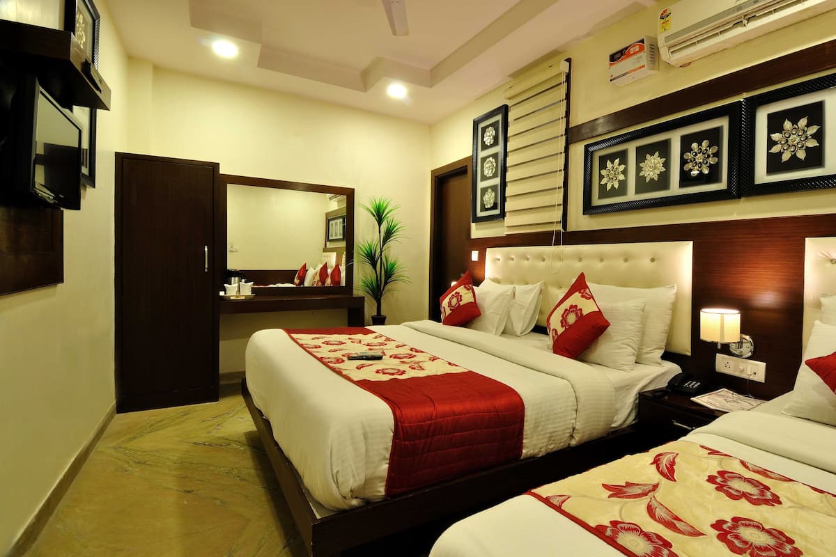 A hotel room with a large bed, a bedside table with a lamp, a mirror, and a wall-mounted air conditioner.