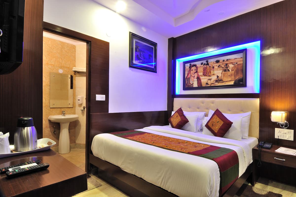 A hotel room with a bed, bedside table, and a nightstand with a lamp.