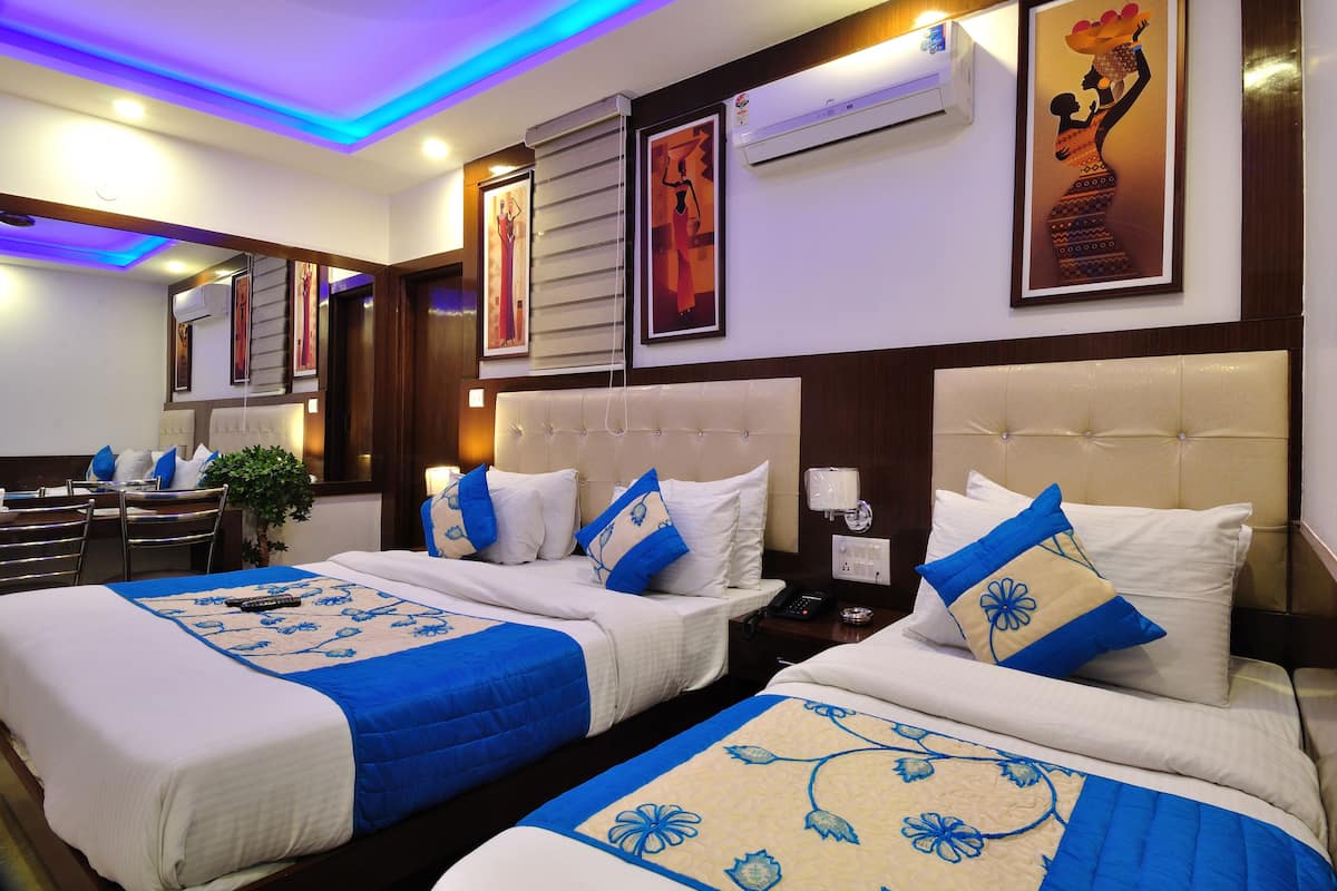 A hotel room with two beds, a dining area, and artwork on the walls.