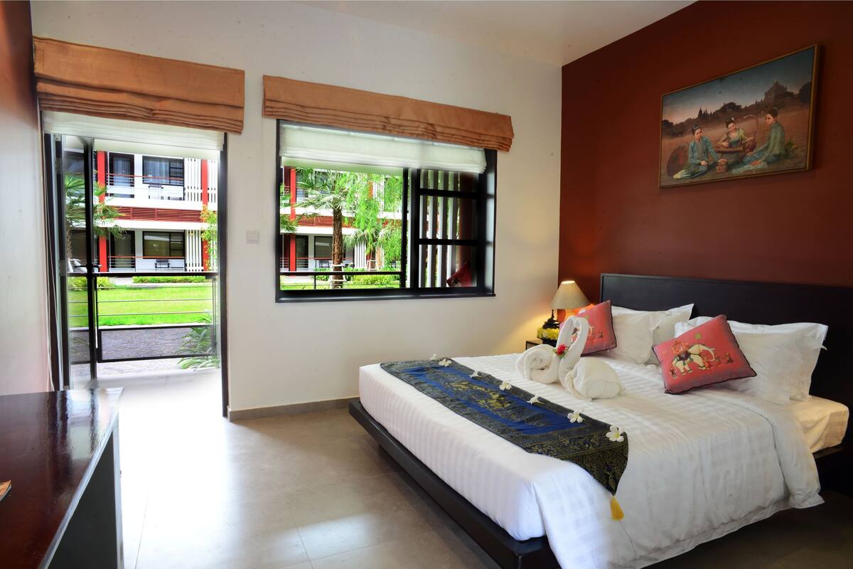 Ein Hotelzimmer mit Bett, einem Gemälde und Blick auf ein Gebäude.