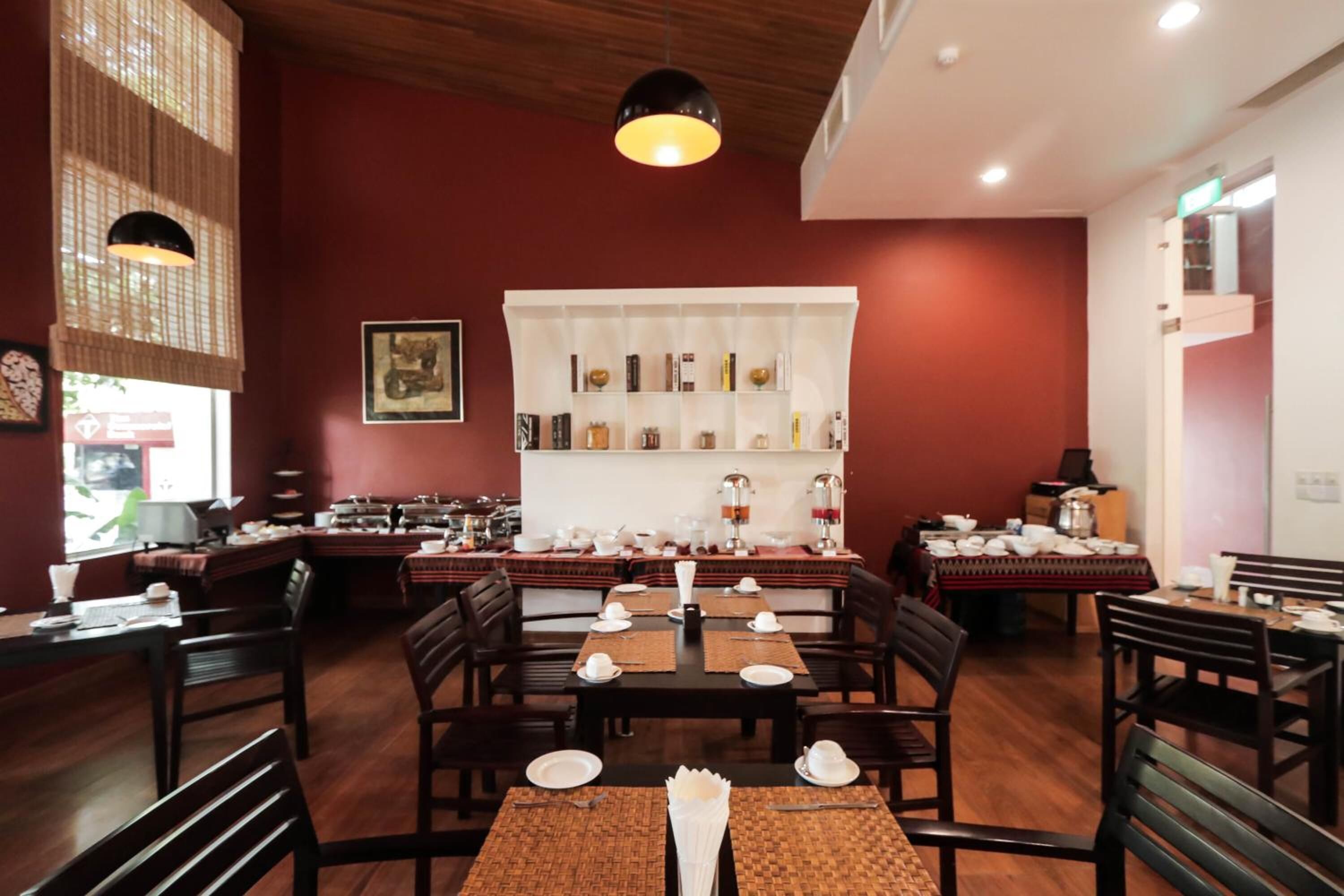 A restaurant with wooden tables and chairs, a white bookshelf, and hanging lights.