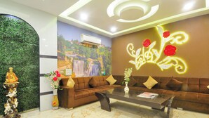 A modern lobby with a sofa, a glass coffee table, a decorative statue, and a mural on the wall. - Check In Room New Delhi Railway Station (New Delhi)