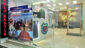 A reception area with a 'Karl Kastele' sign, a 'Sushant Travels' banner, and a 'Welcome Carlo Castle' sign. - Check In Room New Delhi Railway Station (New Delhi)