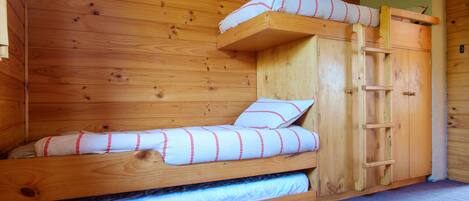 Un lit superposé en bois, avec deux niveaux, une échelle et une petite étagère sur le lit supérieur.