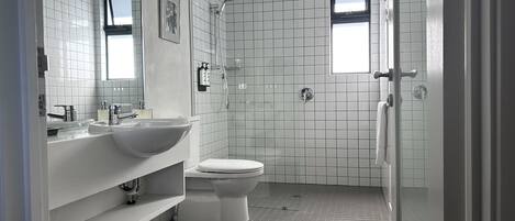 Un baño moderno con lavamanos, inodoro y ducha blancos.