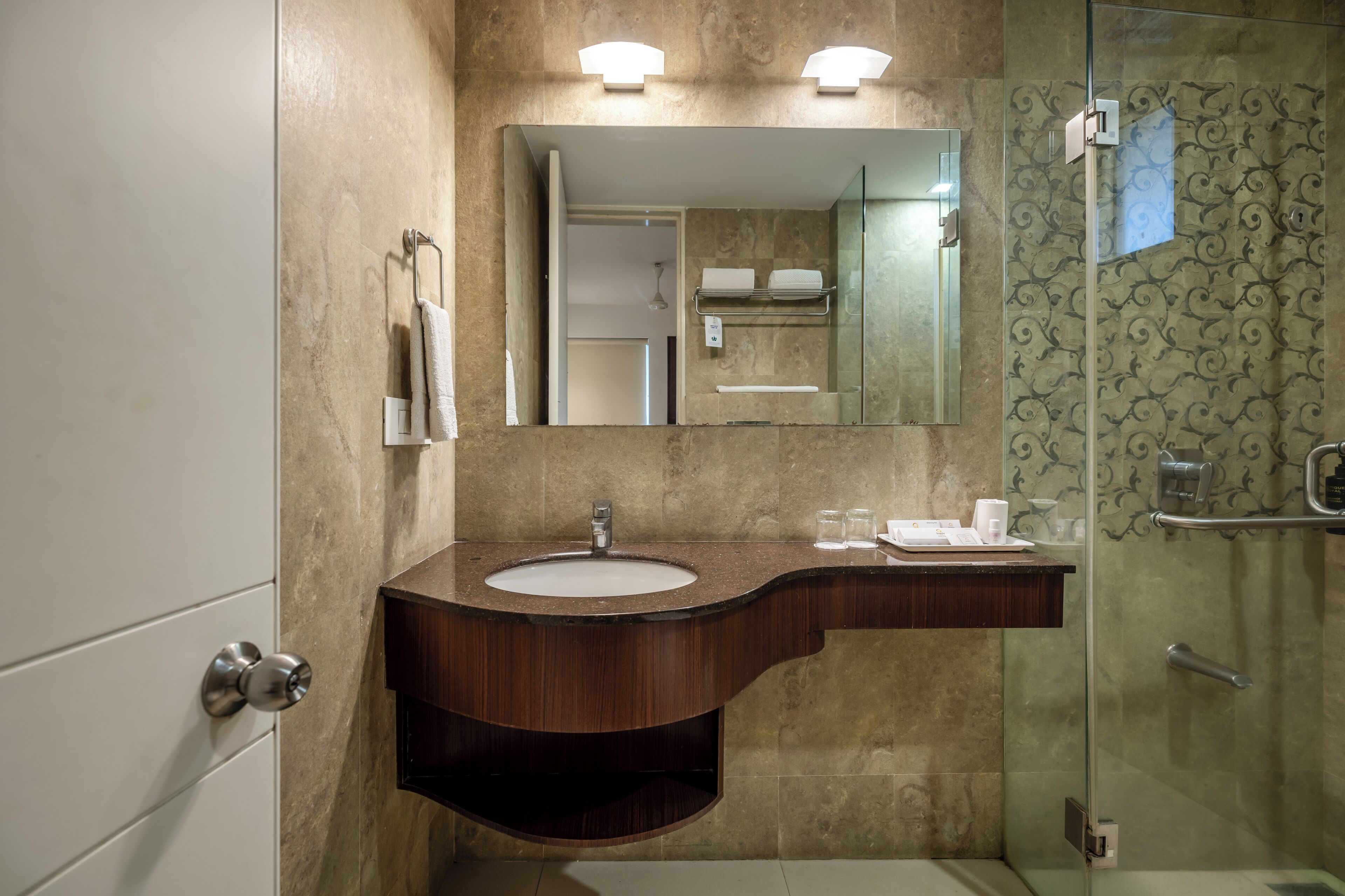 A modern bathroom with a marble sink, a large mirror, and a glass shower enclosure.