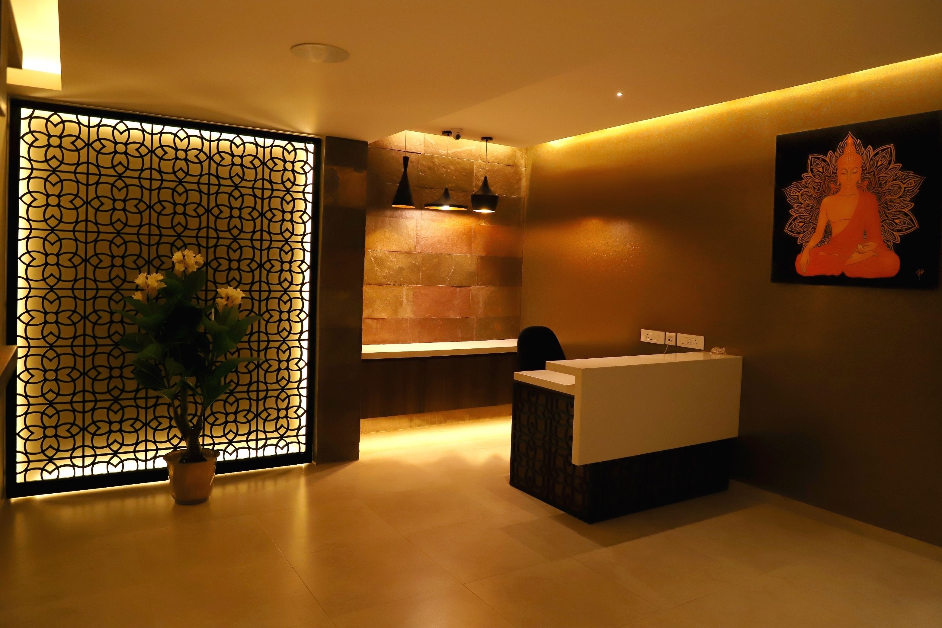 A modern reception area with a reception desk, a decorative wall with a geometric pattern, and a potted plant.