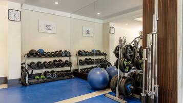 A gym with weight racks, exercise balls, and a squat rack.