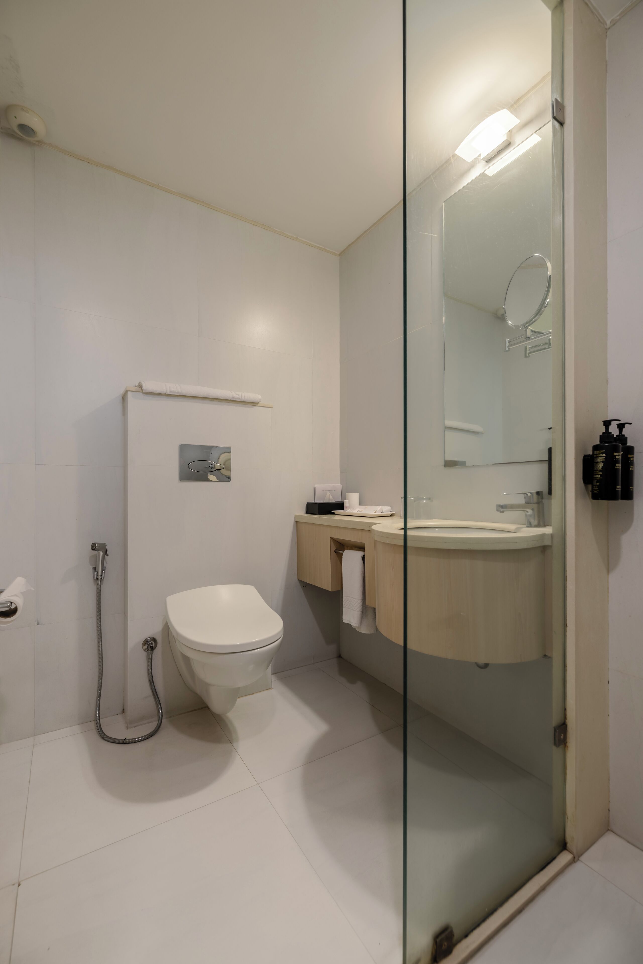 Un baño moderno con cabina de ducha de vidrio, inodoro y tocador con lavamanos y espejo.