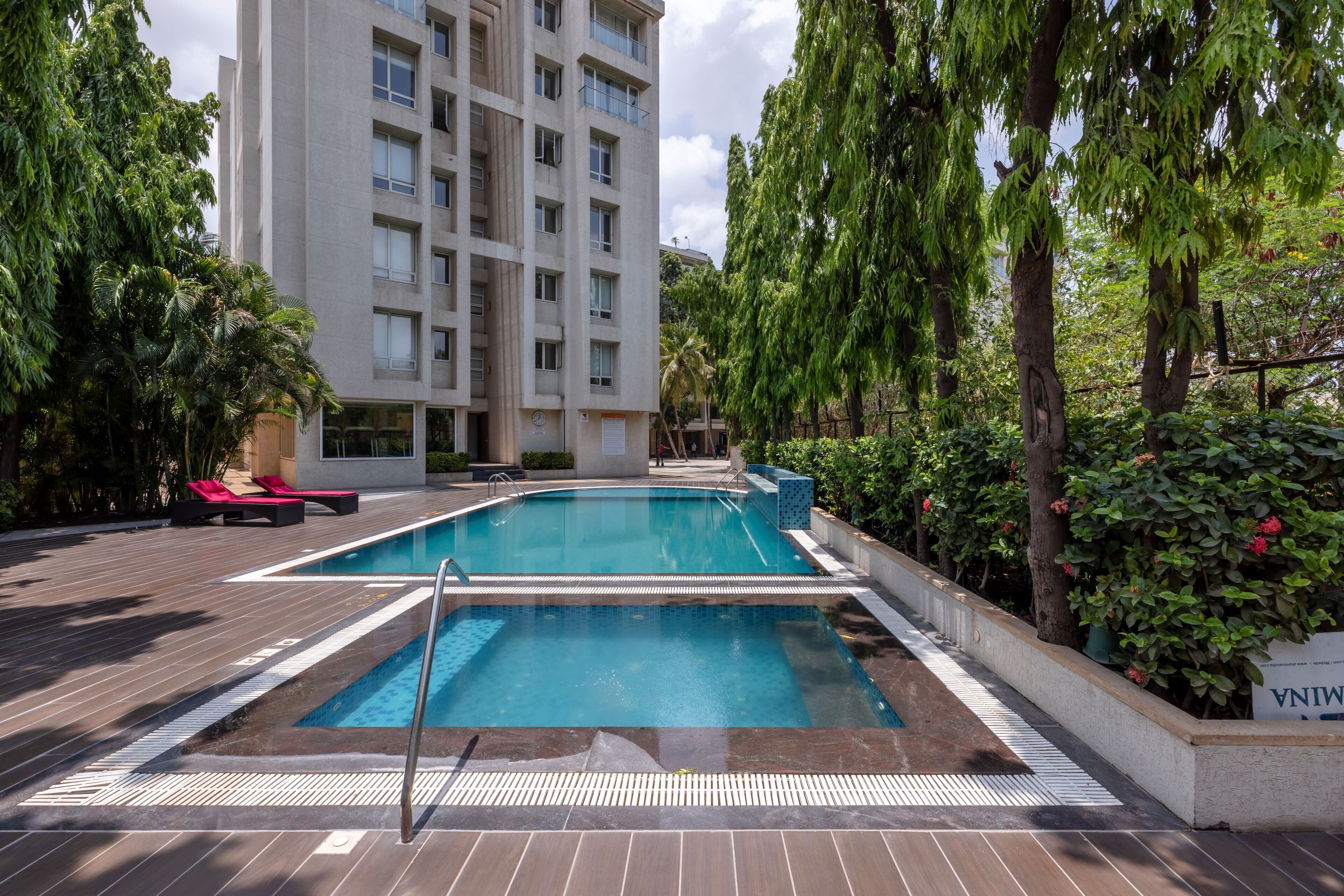 Una piscina amb gandules i un edifici al fons.