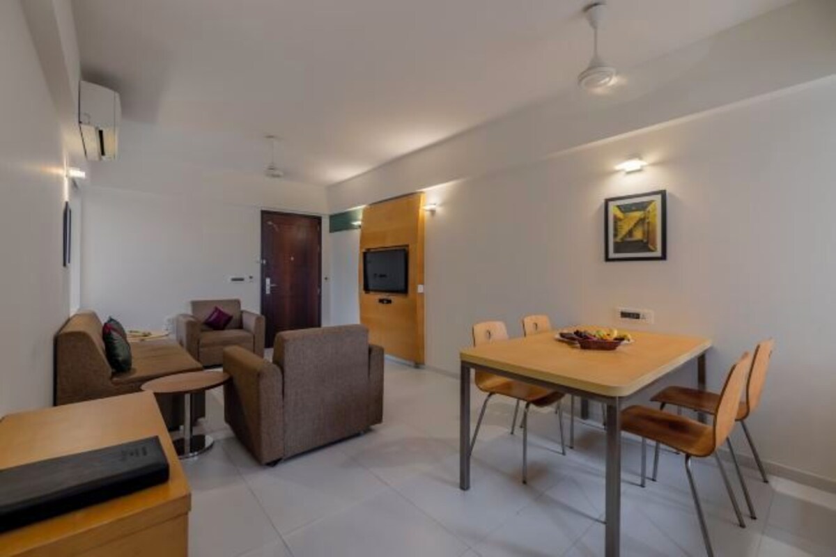 Una sala de estar moderna con un sofá, una mesa de comedor con sillas, un televisor y un cuadro en la pared.