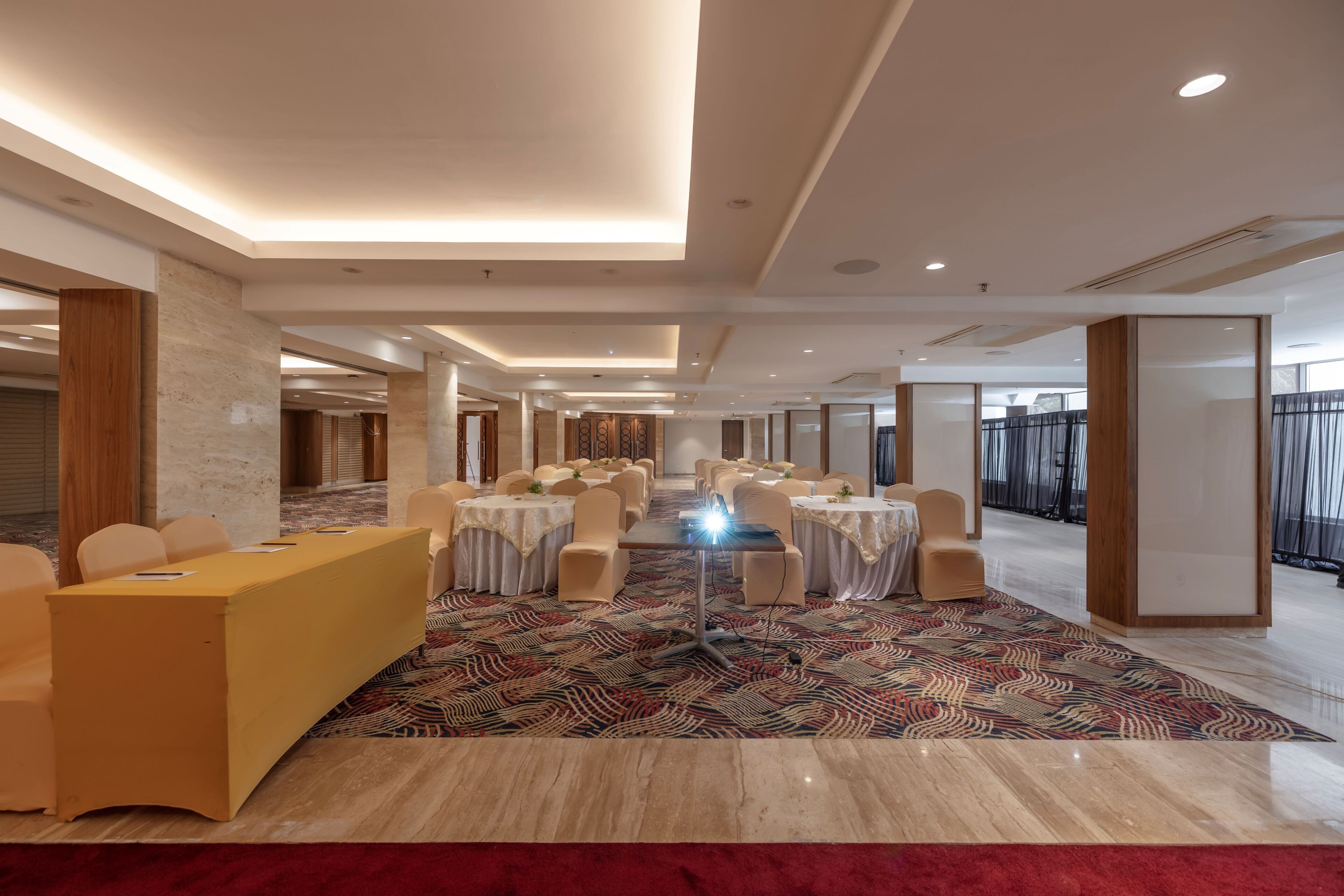 A spacious conference room with a long table, multiple chairs, and a patterned carpet.