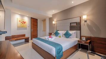 A modern hotel room with a large bed, wooden headboard, bedside table, and a bench.