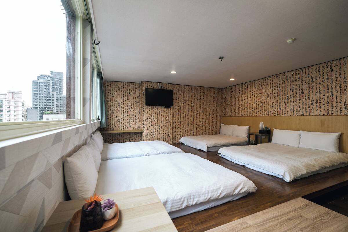A hotel room with two beds, a TV, and a view of the city.