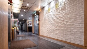 A hotel lobby with a brick wall, wooden flooring, and a reception desk. - Sofu Hotel (New Taipei City)