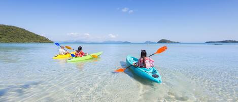 Two kayaks on a calm body of water with clear skies and distant landforms.