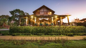 Une maison en bois dotée d’un patio couvert, entourée de verdure.
