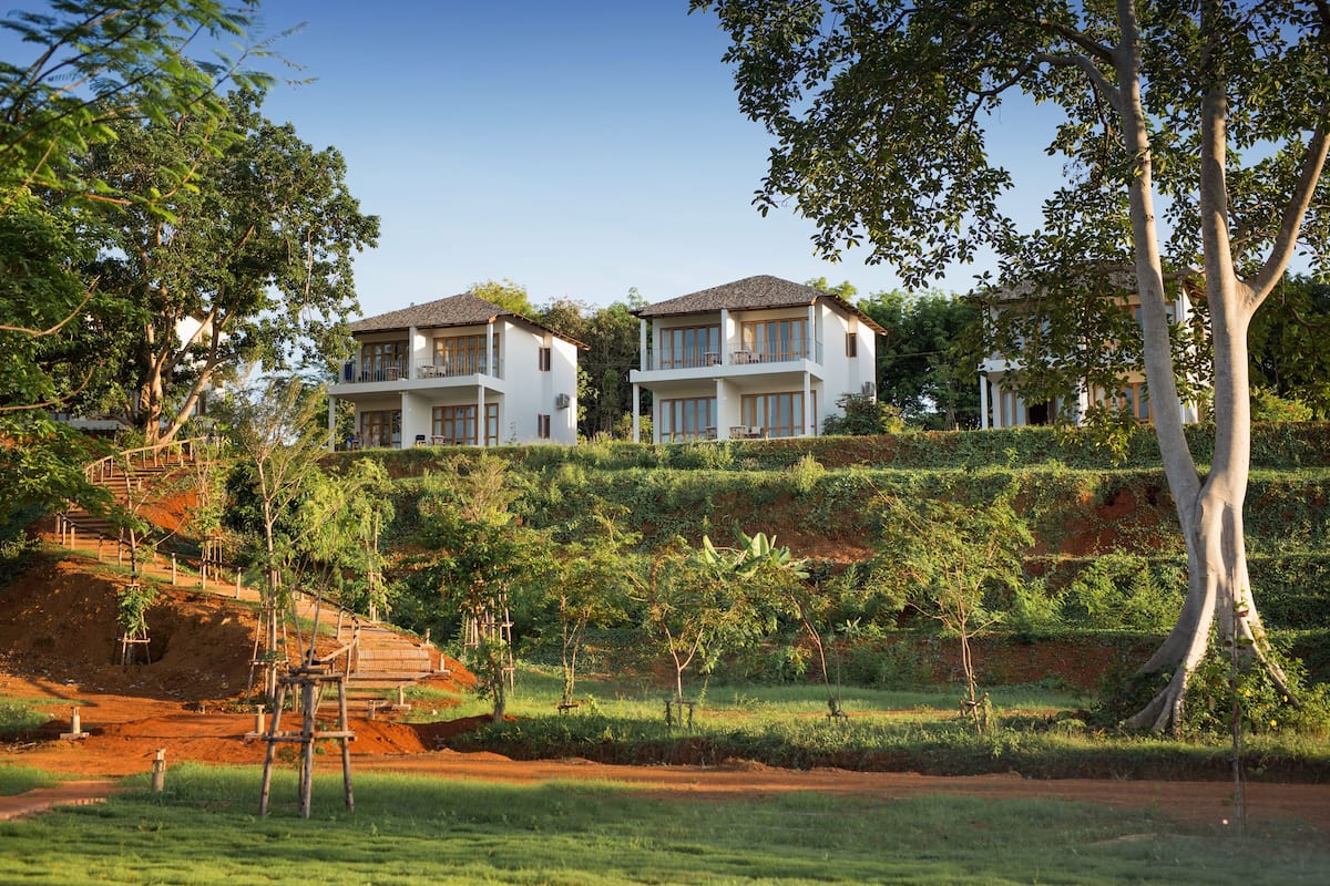 A hillside property with two white buildings, each with multiple balconies and large windows.